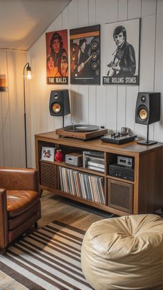 a living room filled with furniture and speakers on top of a wooden shelf next to a brown leather chair