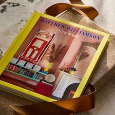 a yellow book sitting on top of a table next to a brown ribbon and chair