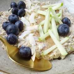 oatmeal with blueberries and apples in a bowl on a gold spoon