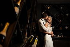 a bride and groom hugging in front of wine bottles