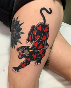 a woman's leg with a tattoo on it and a black lizard holding a red heart