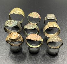 nine ancient roman bronze rings and bracelets with designs on them sitting on a table