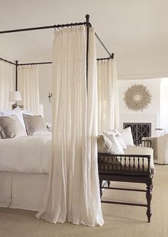 a bedroom with four poster bed and white drapes