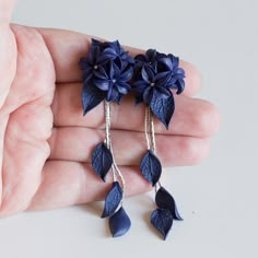 a pair of earrings with blue flowers hanging from it's earwires on a person's hand