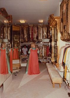 a woman in an orange dress is looking at her reflection in the mirror while another person looks on