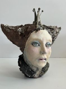 a ceramic sculpture of a woman's head with wings on top of her head