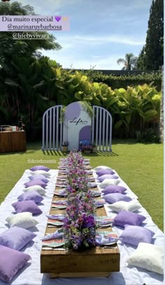 a table with purple and white pillows is set up for an outdoor dinner in the garden