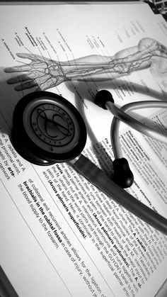 a stethoscope laying on top of an open medical book with the image of a human body