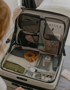 an open suitcase sitting on top of a bed next to a woman's head