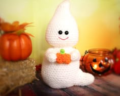 a crocheted bunny holding a carrot in front of pumpkins and other decorations