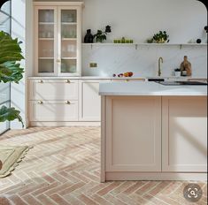 a kitchen with white cabinets and marble counter tops, along with a plant in the corner