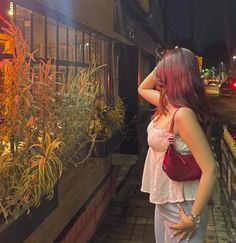 a woman looking at plants in a window