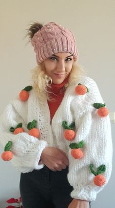 a woman with blonde hair wearing a white sweater and orange pom - poms