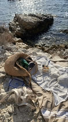 an open umbrella sitting on top of a sandy beach next to the ocean and rocks