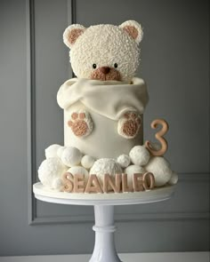 a teddy bear is wrapped in a blanket and sitting on top of a white cake