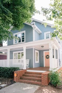 a blue house with white trim on the front porch and steps leading up to it