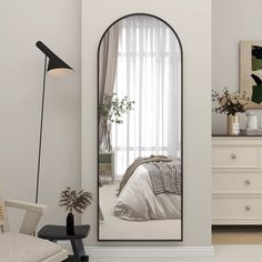 a large mirror in the corner of a room with a bed and chair next to it