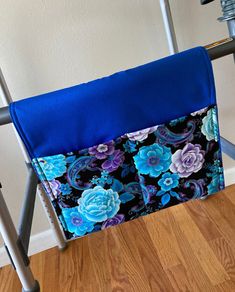 a blue and purple flowered seat cover on a metal frame with a wooden floor