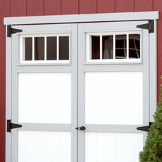 a red building with two white doors and a cat sitting in the window sill