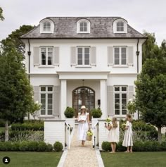 two girls are standing in front of a white house