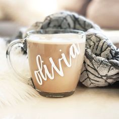 a cup of coffee sitting on top of a white fur covered floor next to a blanket