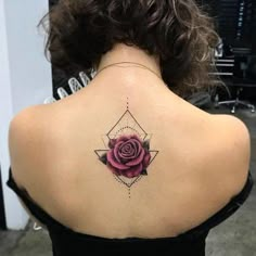 the back of a woman's neck with a rose tattoo on it