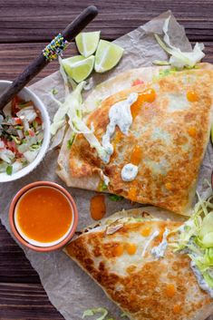 two quesadillas on wax paper with dipping sauces and condiments