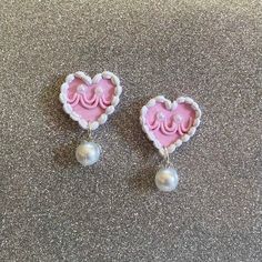 two pink and white heart shaped earrings with pearls on the end of each earring