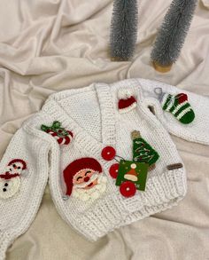 two knitted christmas sweaters with santa and snowmen on them sitting on a bed