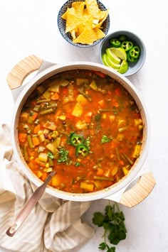 a bowl of soup with tortilla chips on the side and salsa in a bowl next to it