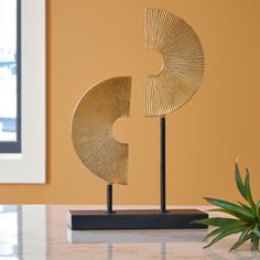 a gold sculpture sitting on top of a table next to a potted plant