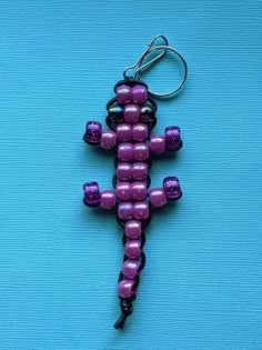 a purple and black beaded lizard keychain on a blue surface