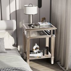 a nightstand with a lamp on top of it next to a bed and a window