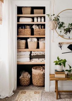 a room with shelves, baskets and plants on the floor next to a bed in front of a mirror