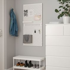 a white shoe rack with shoes on it next to a dresser and coat hanger