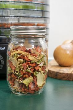 a glass jar filled with food sitting on top of a table next to a cutting board