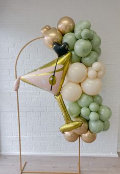 the balloon sculpture is made up of many different colors and shapes, including gold, green, white, and black balloons