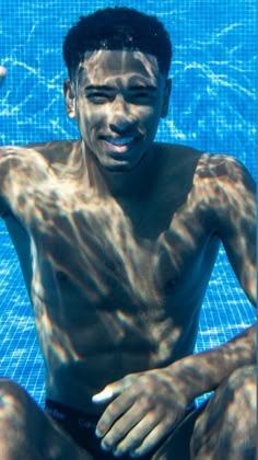 a man sitting in the middle of a swimming pool with his hand up to his face