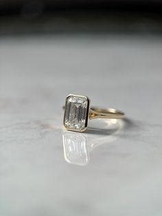 a close up of a ring with a diamond on it's side, sitting on a table