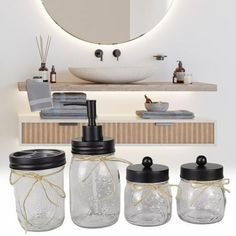 three jars with lids are sitting in front of a mirror and the bathroom sink is lit up