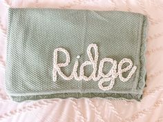 a close up of a blanket with the word ridge written on it in cursive writing