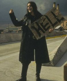 a woman holding up a sign that says hex on it while standing in front of an overcast sky