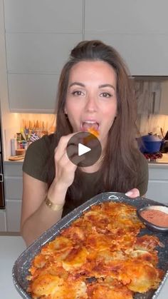 a woman eating food from a pan on top of a counter