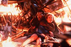 a man and woman sitting next to each other in front of a fire