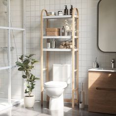 a white toilet sitting next to a wooden shelf filled with bottles and other bathroom items