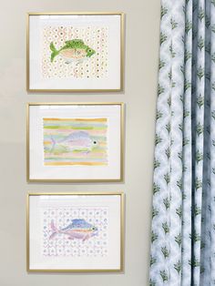 three framed pictures hang on the wall next to a window with blue and green curtains