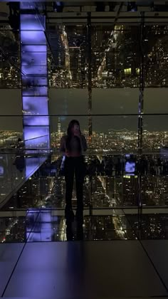 a woman standing in front of a large window at the top of a tall building