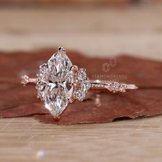 an engagement ring with three pear shaped diamonds on it, sitting on top of a leaf