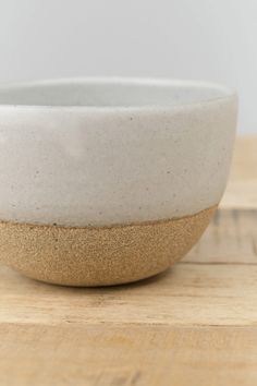 a white and gold bowl sitting on top of a wooden table