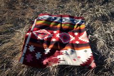 a blanket is laying on the ground in some dry grass, with no one around it